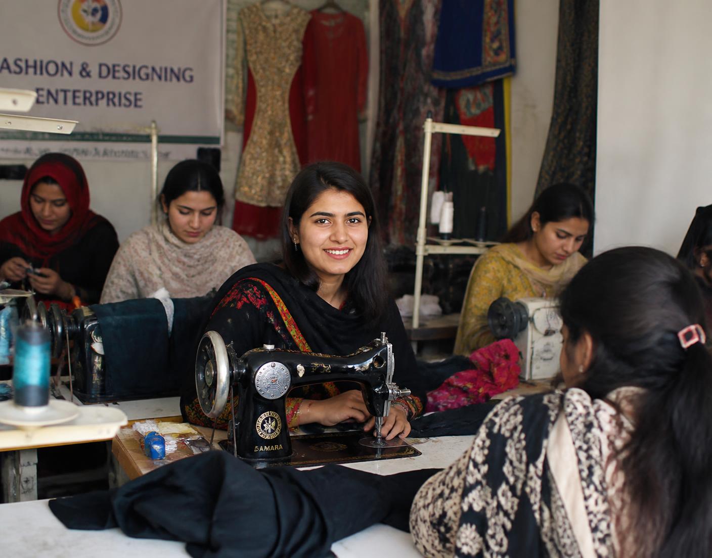 Young women working at sewing machines in a fashion and enterprise training workshop